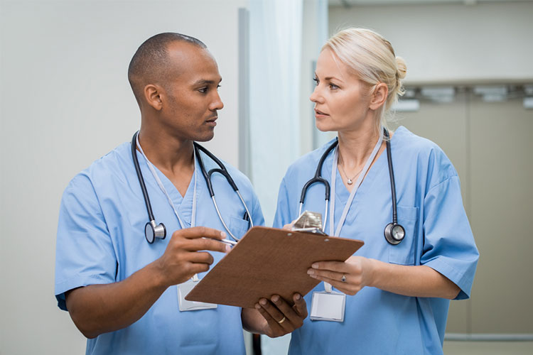 Two nurses consult a patient’s chart.