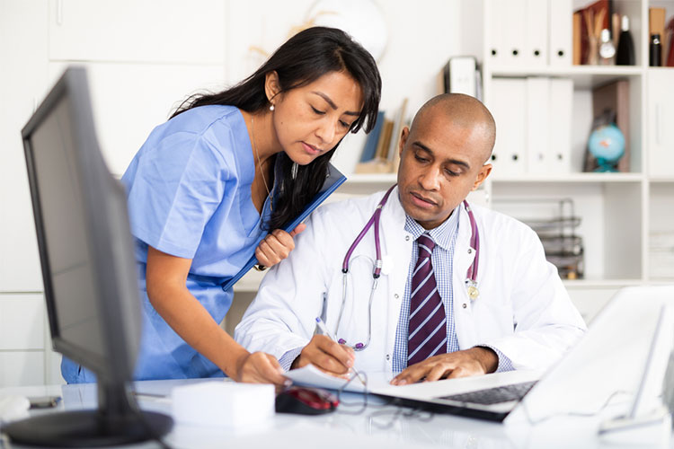A nurse helps a physician fill out a medical form.