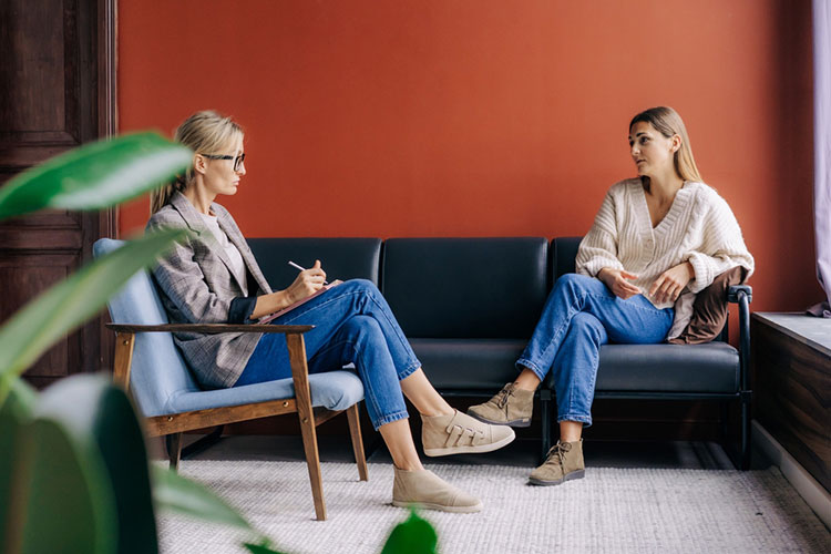 A counselor takes notes while meeting with a client.