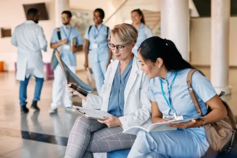 a Nurse Educator sitting with a student in between nursing simulation rounds