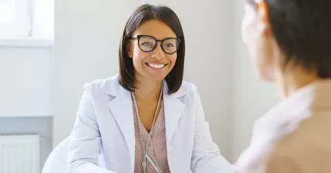 A psychiatric mental health nurse practitioner with a clipboard speaking to a patient. 